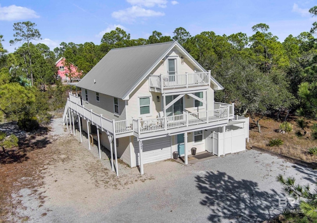 back of property with driveway, metal roof, and a balcony