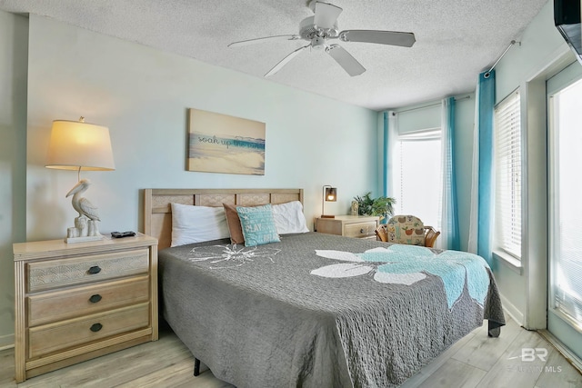 bedroom featuring a textured ceiling, light wood-type flooring, and a ceiling fan