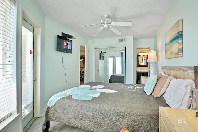 bedroom with connected bathroom, visible vents, a ceiling fan, a closet, and light wood-type flooring