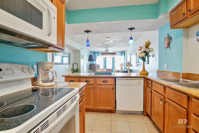 kitchen featuring brown cabinets, white appliances, light countertops, and decorative light fixtures