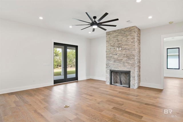 unfurnished living room featuring a fireplace, light hardwood / wood-style flooring, and ceiling fan