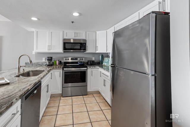 kitchen with white cabinetry, appliances with stainless steel finishes, sink, and stone counters