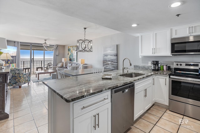 kitchen featuring light tile patterned flooring, appliances with stainless steel finishes, sink, white cabinets, and kitchen peninsula