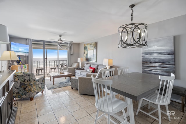 tiled dining room with a water view and ceiling fan with notable chandelier
