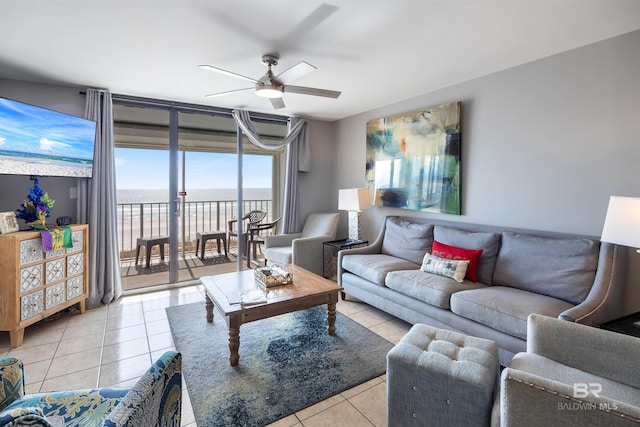 living room featuring light tile patterned floors, ceiling fan, and a water view