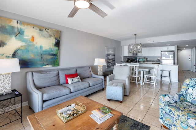 tiled living room with ceiling fan with notable chandelier
