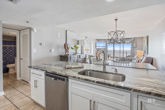 kitchen featuring sink, light tile patterned floors, dishwasher, white cabinetry, and light stone counters