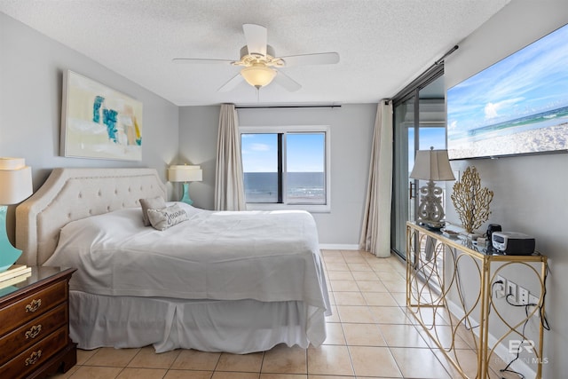 bedroom with ceiling fan, light tile patterned floors, and a textured ceiling