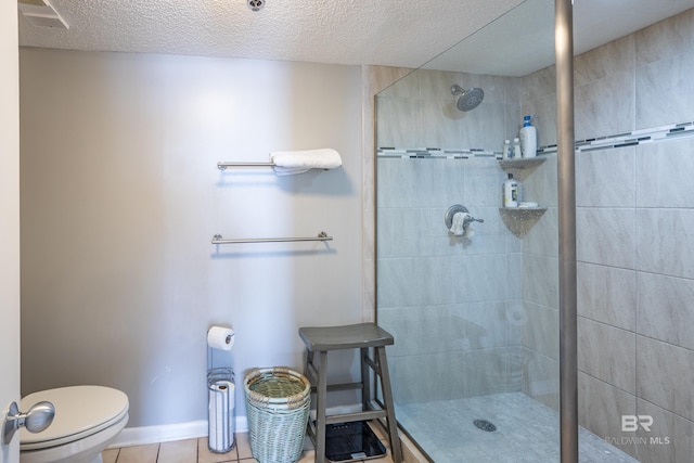 bathroom with tile patterned flooring, a textured ceiling, toilet, and tiled shower