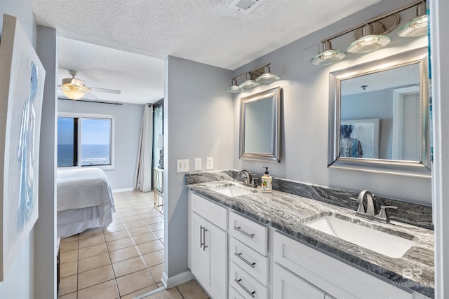 bathroom with tile patterned flooring, vanity, a textured ceiling, and ceiling fan