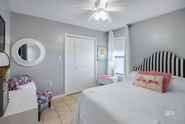 tiled bedroom featuring ceiling fan, a closet, and a textured ceiling