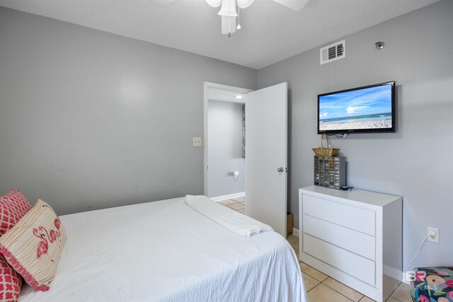 bedroom with light tile patterned flooring, ceiling fan, and a textured ceiling