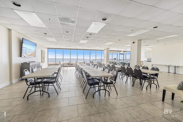 tiled dining room with a paneled ceiling, expansive windows, and a healthy amount of sunlight