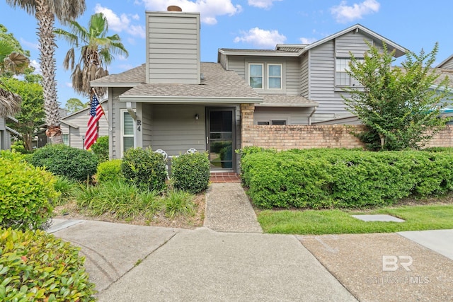 389 Clubhouse Dr Unit 4R, Gulf Shores, AL 36542 - view of front of house featuring a shingled roof, brick siding, and a chimney
