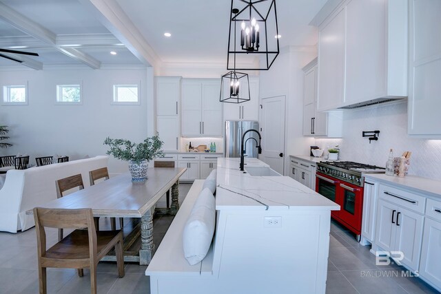 kitchen with stove, white cabinetry, and a center island with sink