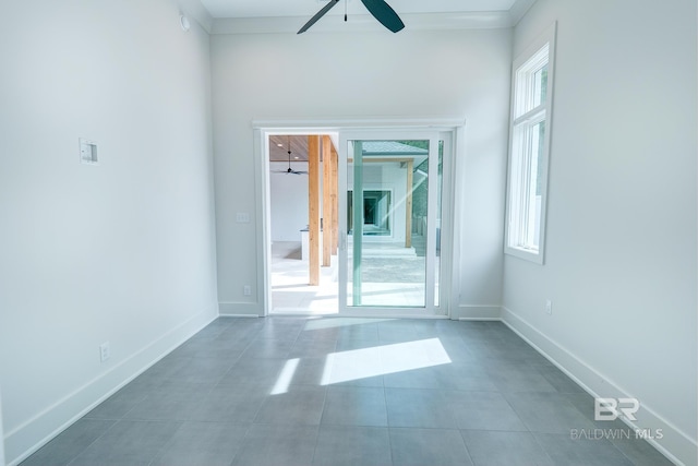 spare room with ceiling fan, dark tile patterned flooring, and a healthy amount of sunlight