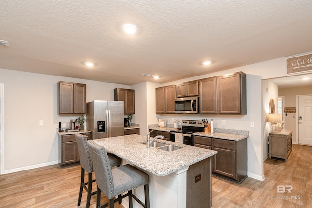 kitchen with light wood-type flooring, appliances with stainless steel finishes, a breakfast bar, and sink