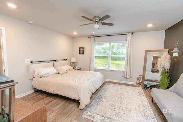 bedroom featuring a textured ceiling, ceiling fan, and light wood-type flooring