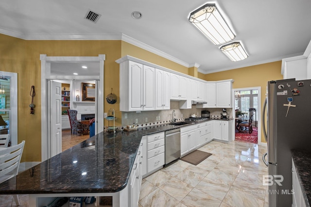 137 Mcintosh Bluff Rd, Fairhope, AL 36532 - kitchen featuring stainless steel appliances, ornamental molding, white cabinets, under cabinet range hood, and decorative backsplash
