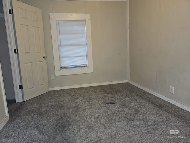 unfurnished room featuring dark carpet