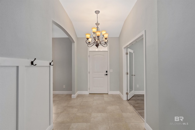 entryway featuring a notable chandelier, baseboards, arched walkways, and light tile patterned floors
