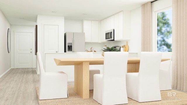 kitchen with white cabinetry, appliances with stainless steel finishes, a breakfast bar area, and light hardwood / wood-style flooring