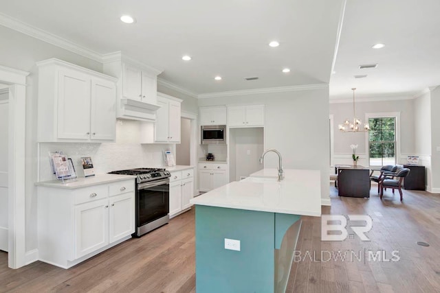 kitchen featuring appliances with stainless steel finishes, sink, an island with sink, light hardwood / wood-style floors, and white cabinets