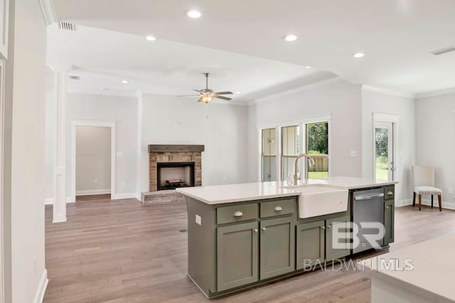 kitchen with light wood-type flooring, sink, an island with sink, dishwasher, and ceiling fan