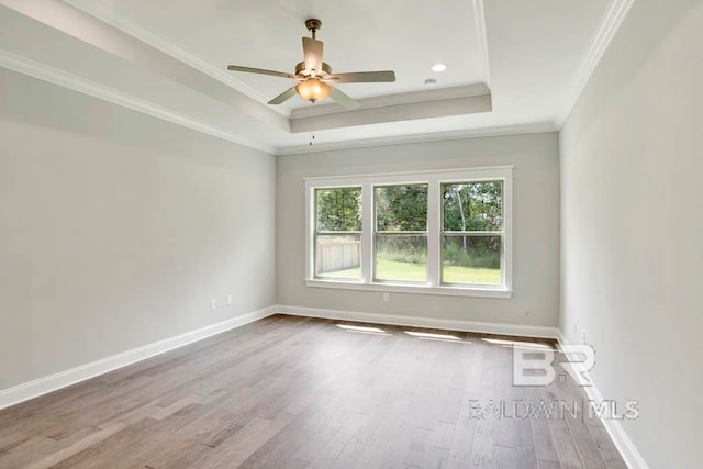 spare room with hardwood / wood-style floors, ceiling fan, a tray ceiling, and ornamental molding