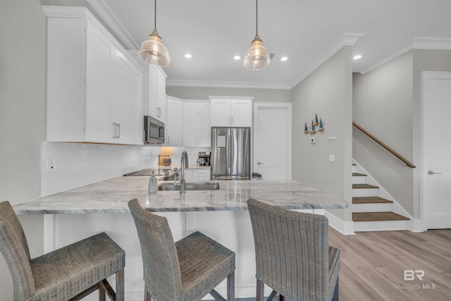 1592 W Beach Blvd, Gulf Shores, AL 36542 - kitchen featuring white cabinets, a breakfast bar area, appliances with stainless steel finishes, and pendant lighting