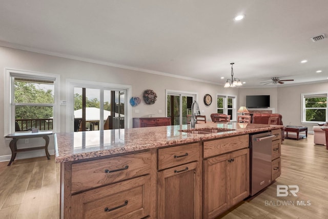 kitchen with a sink, visible vents, light wood-style floors, open floor plan, and light stone countertops