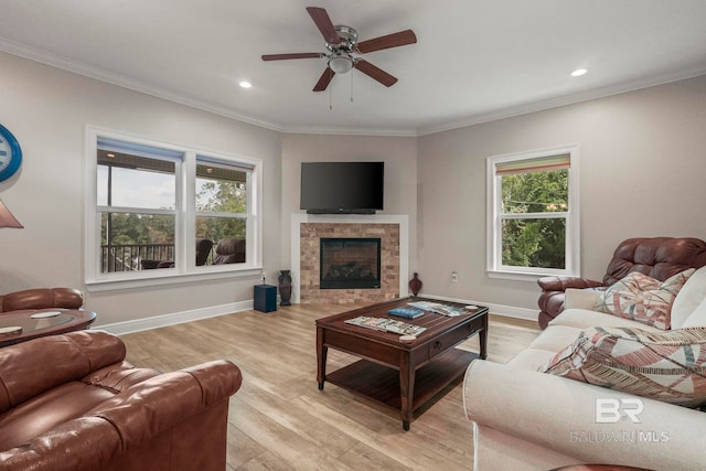 living room with light wood-style floors, a fireplace, baseboards, and crown molding