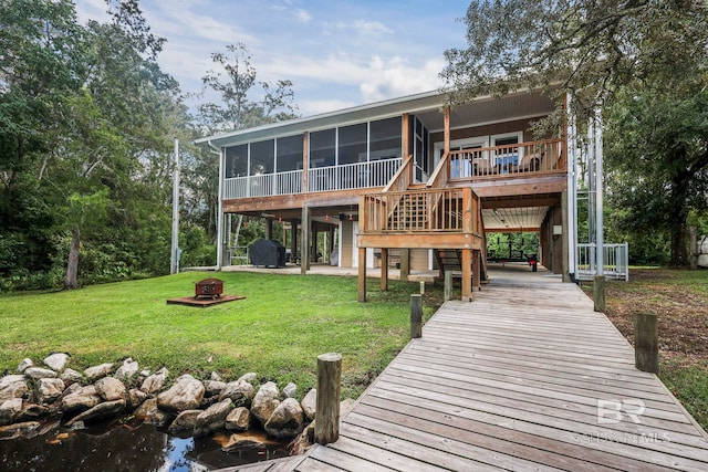 back of property featuring a lawn, an outdoor fire pit, stairway, and a sunroom