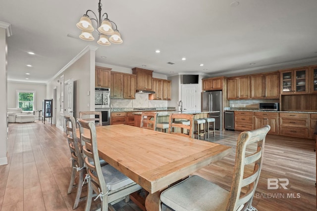 dining room with light wood-style floors, recessed lighting, ornamental molding, and an inviting chandelier