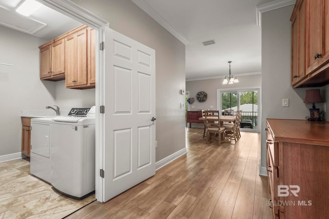 clothes washing area with cabinet space, visible vents, light wood-style flooring, ornamental molding, and washing machine and dryer