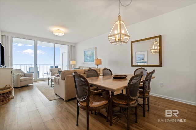 dining area with floor to ceiling windows, hardwood / wood-style floors, and a notable chandelier