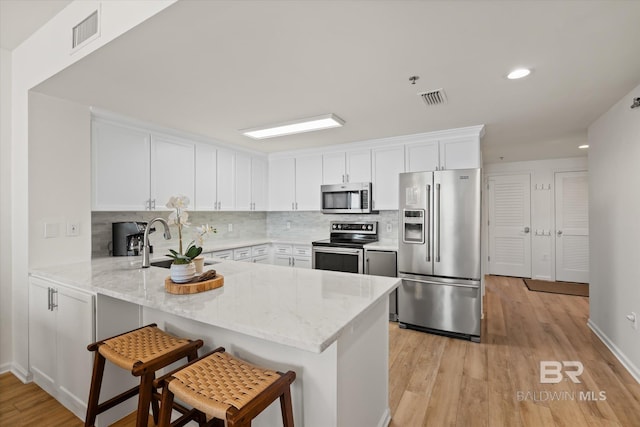 kitchen with white cabinetry, stainless steel appliances, a breakfast bar, and kitchen peninsula