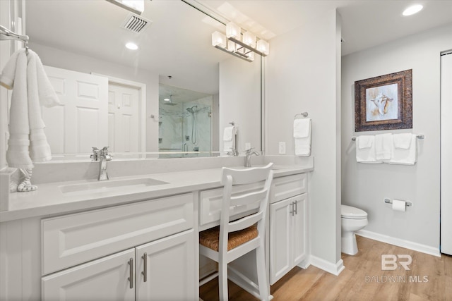 bathroom featuring hardwood / wood-style flooring, vanity, toilet, and walk in shower