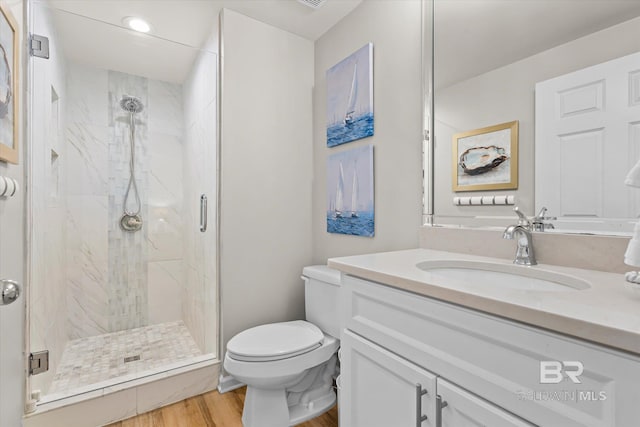 bathroom featuring vanity, hardwood / wood-style flooring, a shower with shower door, and toilet