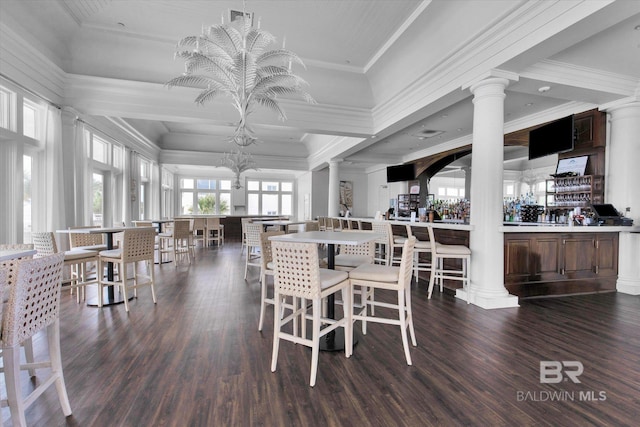 dining space with crown molding, dark hardwood / wood-style floors, a chandelier, and ornate columns