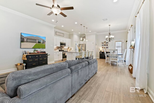 living room featuring ceiling fan with notable chandelier, light hardwood / wood-style floors, and ornamental molding