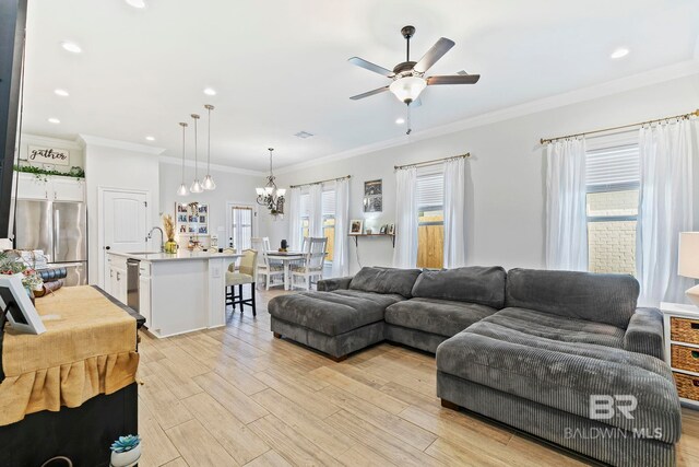 living room featuring sink, ornamental molding, ceiling fan with notable chandelier, and light hardwood / wood-style floors