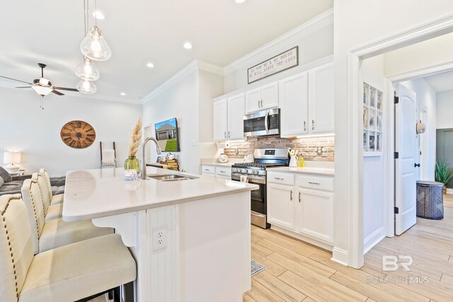 kitchen with light hardwood / wood-style flooring, stainless steel appliances, ceiling fan, and white cabinets