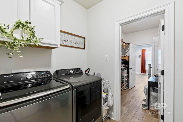 clothes washing area featuring light hardwood / wood-style floors, cabinets, and washer and dryer