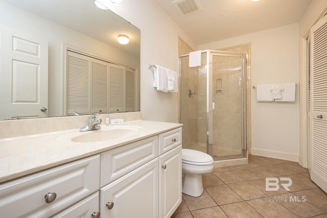 bathroom featuring tile patterned floors, a textured ceiling, an enclosed shower, toilet, and vanity