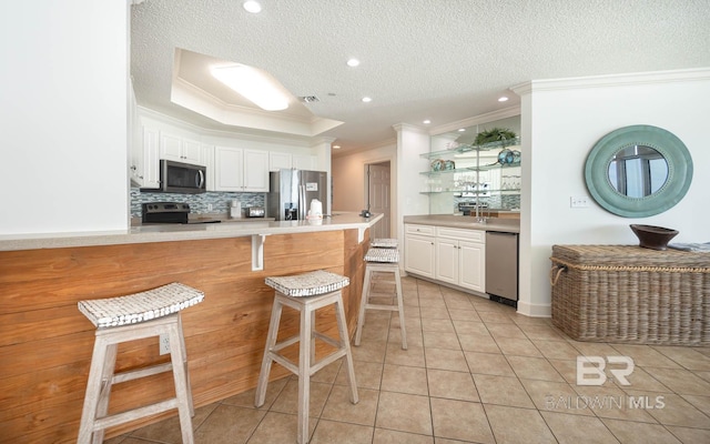 kitchen featuring light tile patterned floors, white cabinetry, a breakfast bar area, and appliances with stainless steel finishes