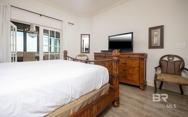 bedroom with hardwood / wood-style flooring, ornamental molding, and a notable chandelier