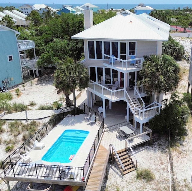 back of property featuring a swimming pool side deck, a balcony, and a patio