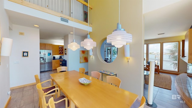 tiled dining space with a towering ceiling and a wealth of natural light