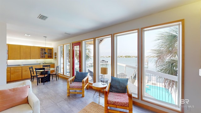 tiled living room featuring plenty of natural light and a water view